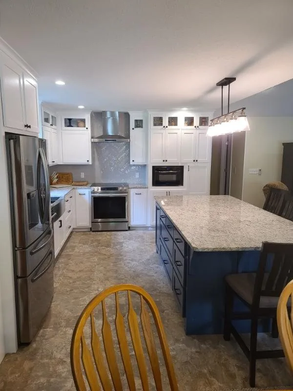 Finished kitchen with white cabinets, a granite island and pendant lighting