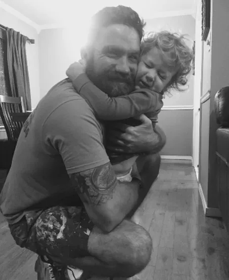 Josh Reynolds holding his son inside a home under renovation