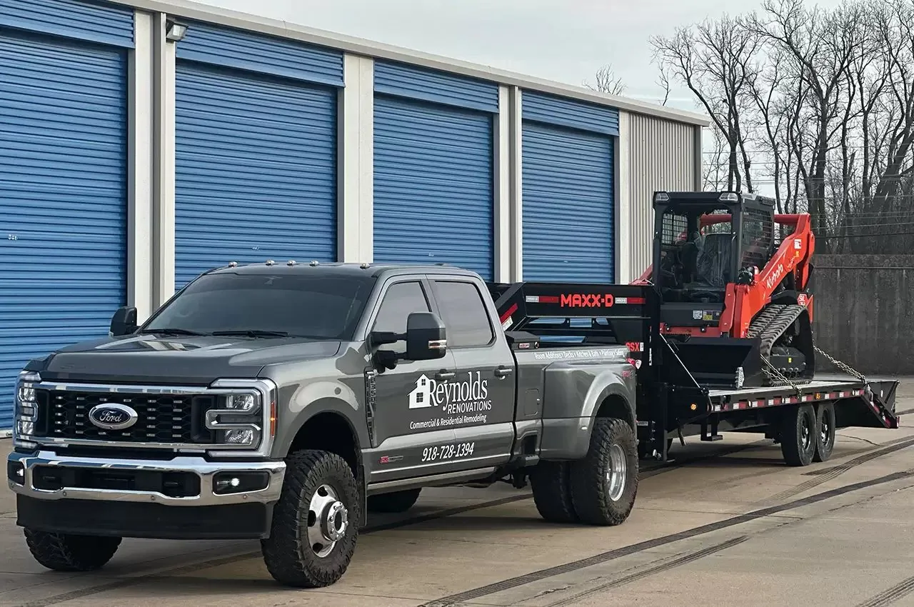 Reynolds Renovations truck with a skid steer loaded on a trailer