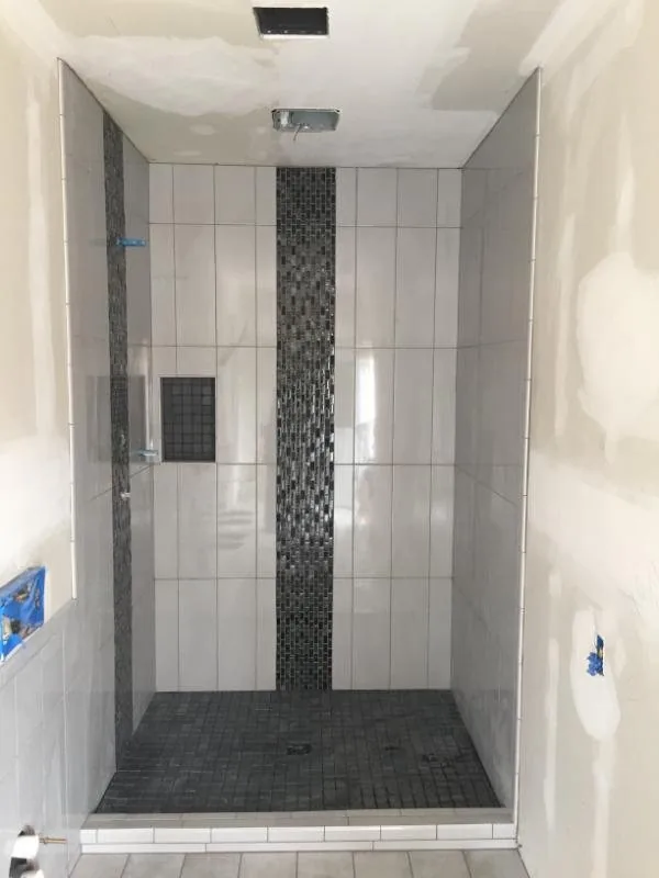 Walk-in shower with white subway tile and a pebble mosaic inlay