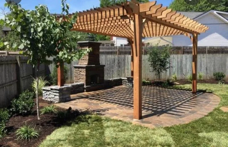 Cedar pergola over a stone patio with an outdoor fireplace