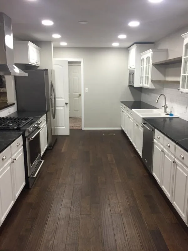 Galley kitchen with white cabinets, stainless range and dark wood floors