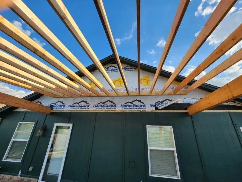 Cedar rafters going up over a covered patio against a blue sky